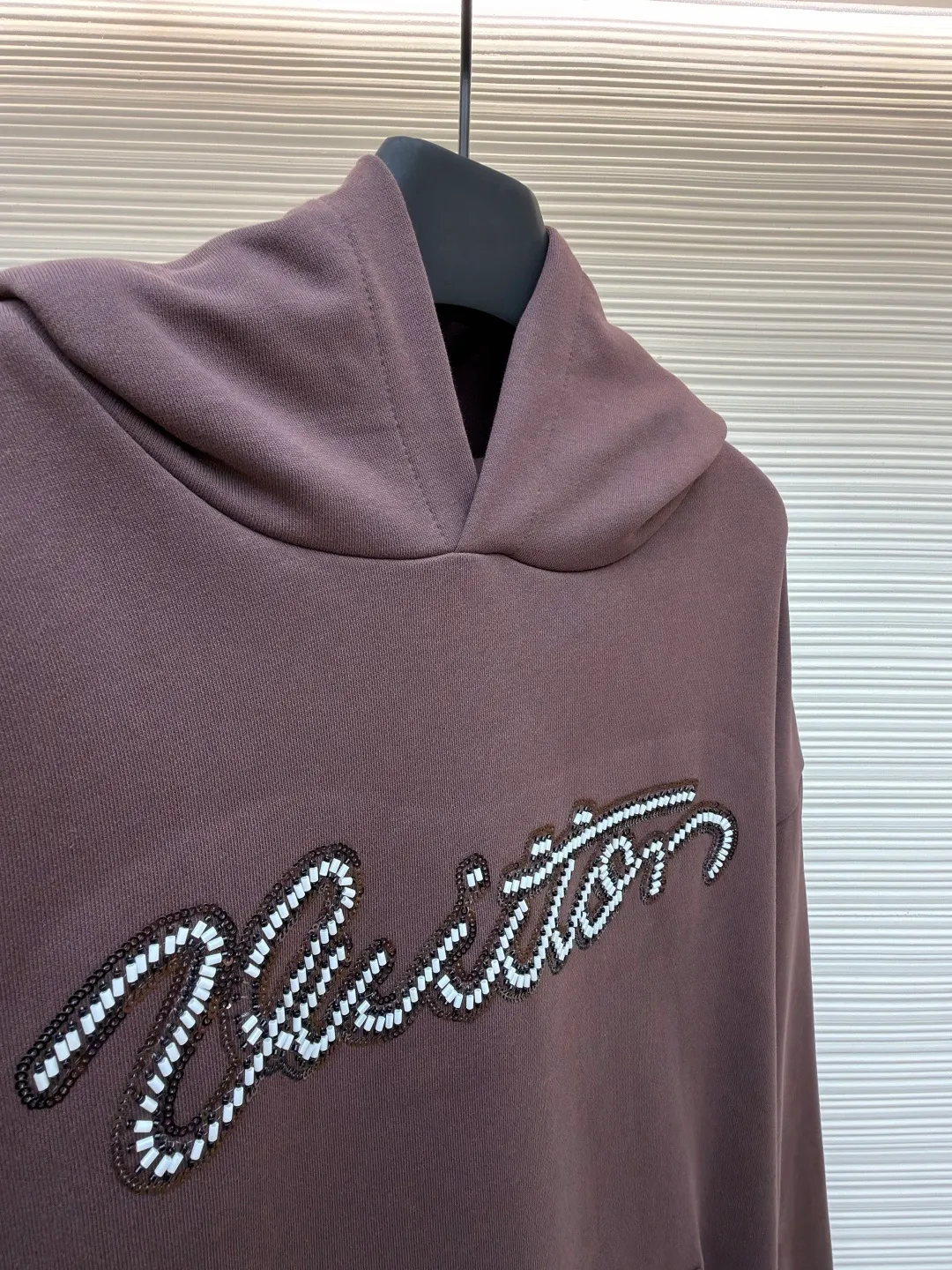 LOUIS VUITTON beaded embroidered letter hooded sweatshirt ●Item number: 1682118-A60 ●Material: pure cotton fish scale base fabric ●Technology: Pearl embroidery production ●Color: brown ●Version: fitted version ●Weight: about 830 grams ●Size: S-M-L-XL ●Description: The fabric is made of 26S double yarn + 10S fish scale bottom brushed fabric, weight 380g, with 21S double yarn 2*2 rib, weight 380g. This kind of fabric is treated with fleece to form a layer of soft and plump fluff on the inside; the improved fish scale knitting method forms a delicate concave and convex texture on the bottom surface, similar to the arrangement of fish scales. Effectively increases the air storage layer and improves thermal insulation performance. The front of the fabric is smooth and smooth, while the back is soft and waxy. It has excellent moisture absorption, breathability, wrinkle resistance and drape, and is thicker and crisper than ordinary sweatshirt materials. It gives clothes excellent warmth retention, breathability and skin-friendly touch. The Vuitton script on the chest is embroidered with beads. During the embroidery process, tiny beads are fixed on the fabric together with embroidery thread. The direct characteristics brought by this process are a strong three-dimensional sense, a unique sense of weight and a reflective effect that changes with the light. The overall wiring is straight and delicate, the fabric is comfortable and soft, and the color is consistent without color difference. It can be matched with the same style to create a fashionable look and control various occasions. Customized accessories, complete with three standards, same style for men and women!